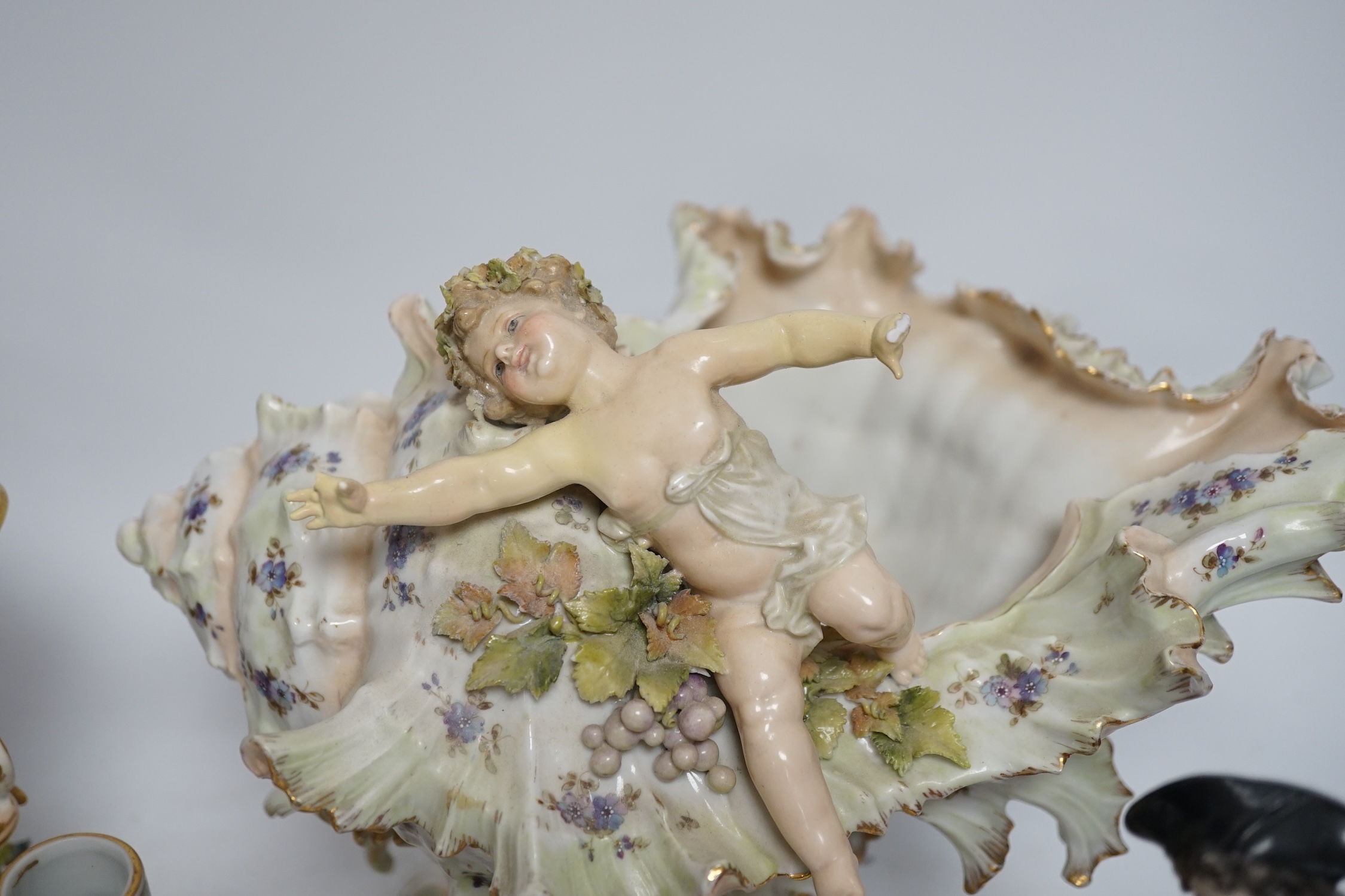 A porcelain shell-shaped centrepiece, a Dresden pill box, a pair of taper holders and a porcelain figure, tallest 21cm